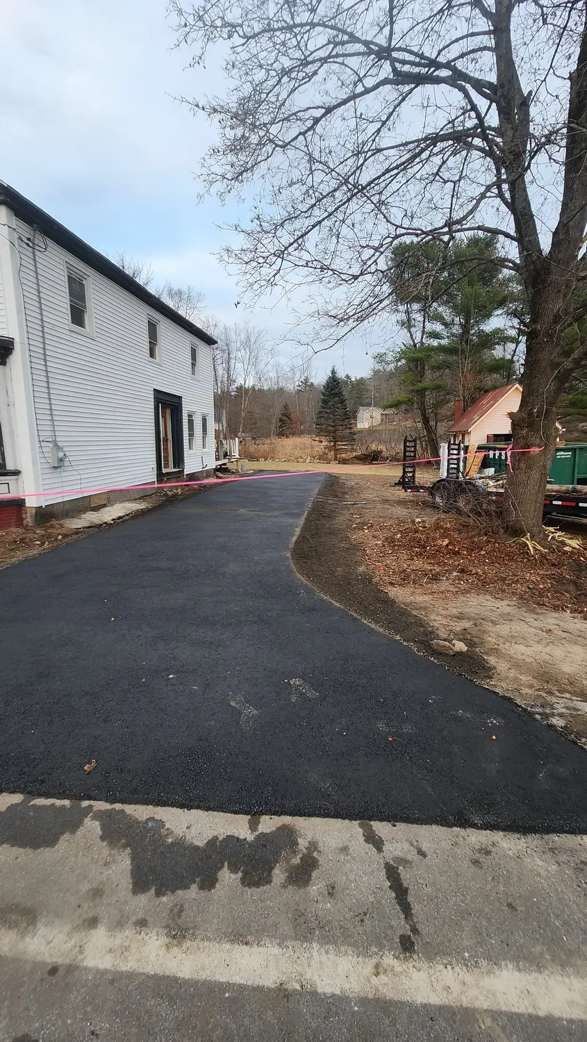 Clean new asphalt driveway beside a white building